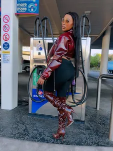 Chic burgundy patent leather cropped jacket and matching high boots in a gas station