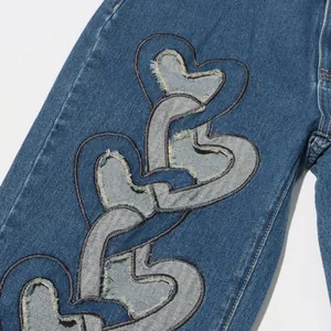 Detailansicht der herzförmigen Patchwork-Details an einer blauen Jeans mit hoher Taille.