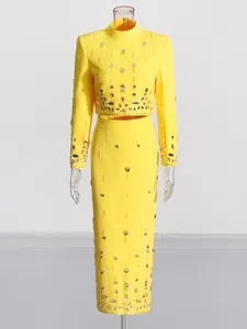 Elegant yellow two-piece set featuring beaded rhinestone crop top and high-waisted midi skirt.