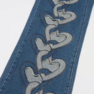 Detailansicht überlappender Herz-Applikationen mit ausgefransten Kanten auf Jeans.