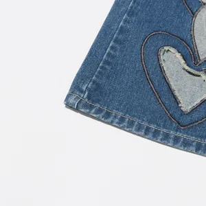 Detailansicht eines herzförmigen Ausschnitts an einer blauen Jeanshose mit Fransen