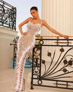 Elegant white sequin evening gown with pearl embroidery and feather trim detail.