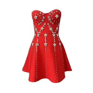 Detail van een rode strapless jurk met zware strass versieringen in bloemen- en lijnpatroon