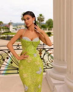 Dettaglio dell'abito da sera verde lime con paillettes e motivi a farfalla argentati.