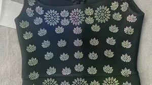 Detailed close-up of a black bandage dress bodice with iridescent rhinestone patterns.