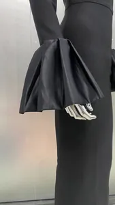 Close-up of dramatic pleated flare sleeves on an elegant black evening dress.