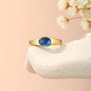 Detailaufnahme eines vergoldeten Kupferrings mit einem leuchtend blauen Zirkon-Stein