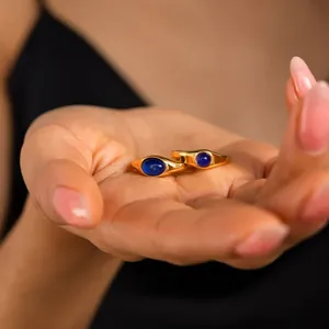 Detailansicht eleganter vergoldeter Ringe mit blauen ovalen Zirkonsteinen in der Hand