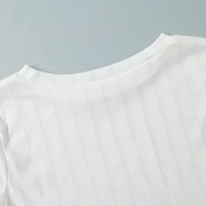 Close-up of white knitted pajama top with heart jacquard and ribbed texture details.