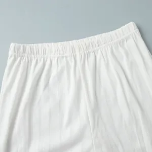 Close-up detail of white knitted pajama pants with heart pattern and elastic waistband