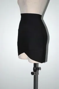 Detail view of a black bandage mini skirt featuring a stylish criss-cross hemline