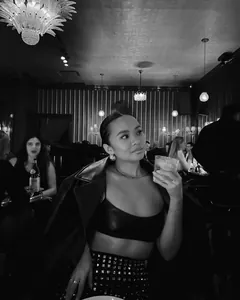 Close-up of a chic woman wearing a black studded mini skirt in a sophisticated bar setting