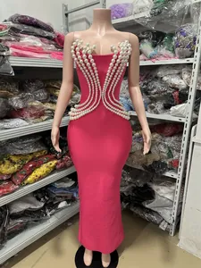 Floor-length pink bodycon dress featuring elaborate pearl beadwork on a mannequin stand.