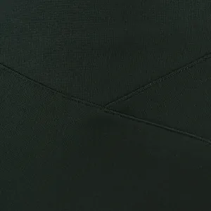 Macro view of the tight knit texture and crossover seam detail on a black bandage skirt.