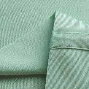 Close-up macro detail of mint green bandage dress fabric showing premium ribbed knit texture