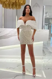 Elegant white off-shoulder mini dress featuring exquisite pearl beading and draped sleeves