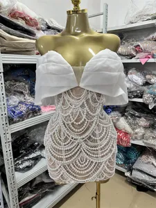 Detailed view of elegant white mini dress with intricate pearl beaded scalloped patterns