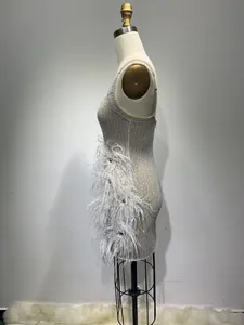 Detailed side view of a white sequined mini dress with elegant feather trim design