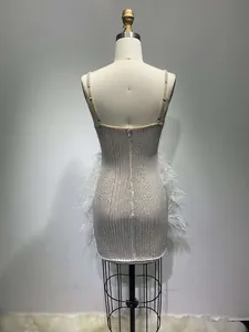 Back view of a white sequined mini dress with feather trim and beaded straps