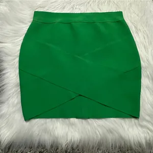 Detail view of a vibrant green crossover bandage mini skirt on white faux fur background.