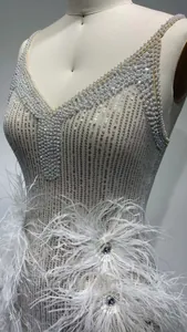 Detailed view of silver sequin performance dress with white feathers and pearl straps