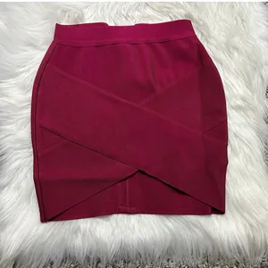 Macro view of burgundy bandage mini skirt with cross-front design on white faux fur background