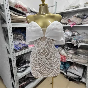 Elegant white beaded strapless mini dress with ruffled bodice and intricate pearl patterns.
