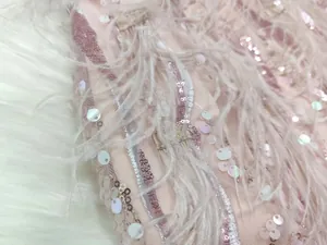 Detailed macro view showing the intricate pink sequins and delicate feather trim on evening dress