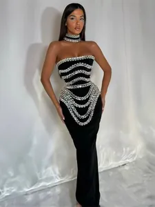 Detailed view of black strapless bandage maxi dress with intricate rhinestone draped patterns