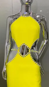 Close-up of yellow halter dress featuring waist cutouts and sparkling rhinestone trim.