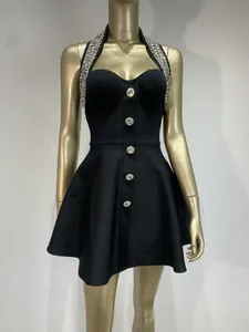 Close-up detail of black halter neck dress with rhinestone trim and decorative buttons.