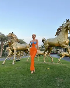 Una modella indossa un vivace abito lungo arancione e blu con ritagli sui fianchi.
