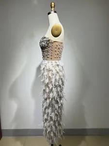 Dettaglio laterale di un lussuoso abito da gala senza spalline con strass e piume.