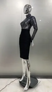Vue latérale d'une robe bandage noire avec détails en strass sur un mannequin argenté brillant.