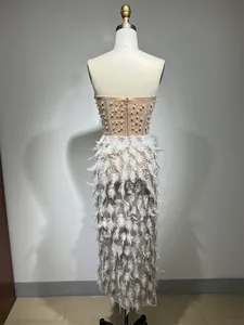 Vista posteriore di un abito beige di lusso con strass, perle e piume bianche eleganti