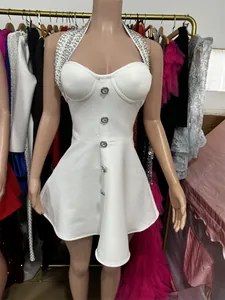 Close-up of white halter party dress featuring rhinestone neckline and decorative buttons.