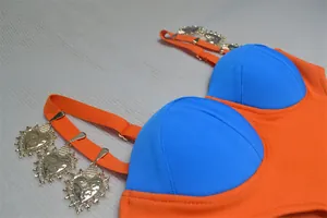 Primo piano dell'abito color-block blu e arancione con ciondoli a cuore dorati sulle spalline