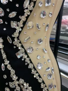 Close-up showing intricate luxury rhinestone beading on a black sheer bandage evening gown