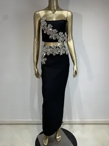 Detalle de flores de pedrería en top de tubo negro y falda larga a juego