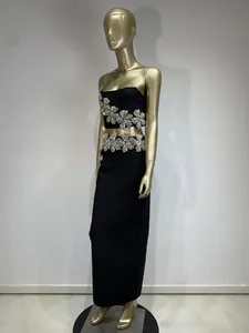 Detalle de conjunto de fiesta negro de dos piezas con flores de pedrería en maniquí dorado