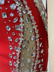 Detailed view of sparkling rhinestones and sheer mesh on a luxury red evening dress.