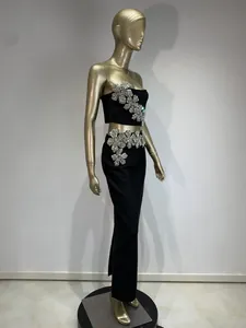 Vista lateral del conjunto de fiesta negro con detalles de flores de strass en el top y falda
