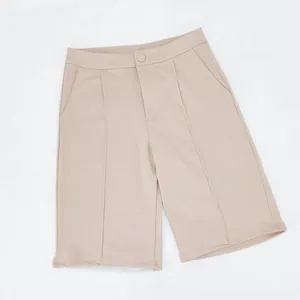 Vista detallada de los pantalones cortos de traje beige con cintura alta y textura de la tela