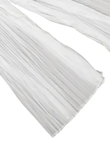 Detailed view of white pleated wide-leg trousers showing fabric texture and fine pleats.