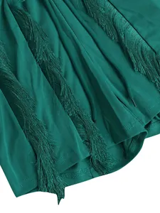 Close-up detail of luxury emerald green fringe tassels on a minimalist solid color romper