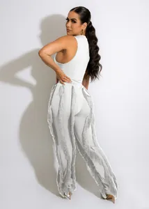 Detailopname van witte tweedelige set met broek met lange franje kwastjes.