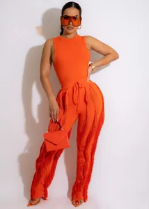 Model draagt een oranje tweedelige fringset met bijpassende handtas en zonnebril.