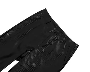 Detailed macro view of black faux leather trousers with embossed crocodile texture