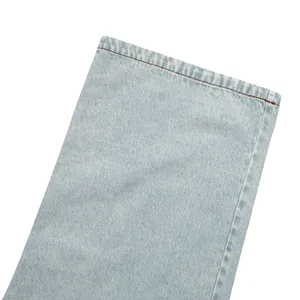 Macro view of light blue straight leg denim jeans hem with brown contrast stitching