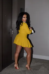 Back view of yellow two-piece office suit set featuring a stylish pleated mini skirt
